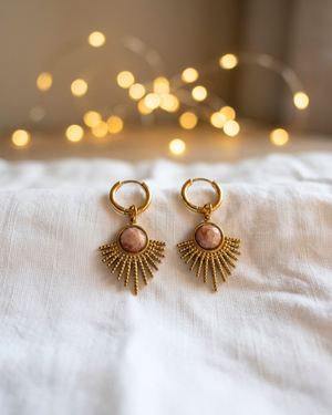 Orecchini Sevilla Giunquilla in oro 18k con eliolite, pietra del sole e luminosità Orecchini dorati Giunquilla con amazzonite, energia di espressione autentica e protezione Orecchini Giunquilla a raggi in acciaio placcato oro 18k con eliolite verde su sfondo naturale Orecchini Sevilla Giunquilla con amazzonite, per donne che occupano spazio con gioia Orecchini pendenti Giunquilla con pietra del sole, stile boho chic ispirato al folklore andaluso
