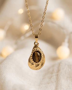 Collana Gotita Giunquilla in oro 18k con occhio di tigre, amuleto di protezione e forza Ciondolo Gotita Giunquilla con occhio di tigre, pietra del discernimento e della determinazione Collana pendente in acciaio placcato oro Giunquilla con occhio di tigre, stile retrò e sacro femminile Ciondolo Giunquilla con occhio di tigre su catena dorata, energia di radicamento e volontà Collana Gotita Giunquilla, oro 18k e occhio di tigre: un amuleto antico per la donna contemporanea
