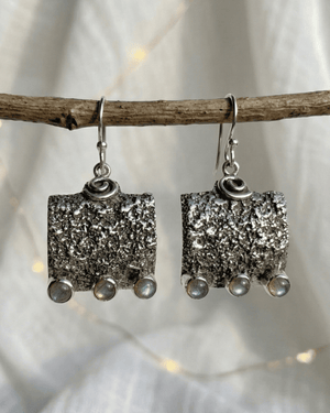 Orecchini pendenti Wayra Giunquilla in argento 925 con labradorite, equilibrio tra terra e luna Orecchini Giunquilla con labradorite cangiante in argento 925, radicamento e flusso ciclico femminile Orecchini quadrati pendenti Giunquilla in argento con labradorite e spirale, simboli del cosmo Orecchini Wayra Giunquilla argento 925 e labradorite: energia terrestre e ritmo interiore al lobo Orecchini pendenti Giunquilla con labradorite in argento 925, gioiello spirituale del sacro femminile
